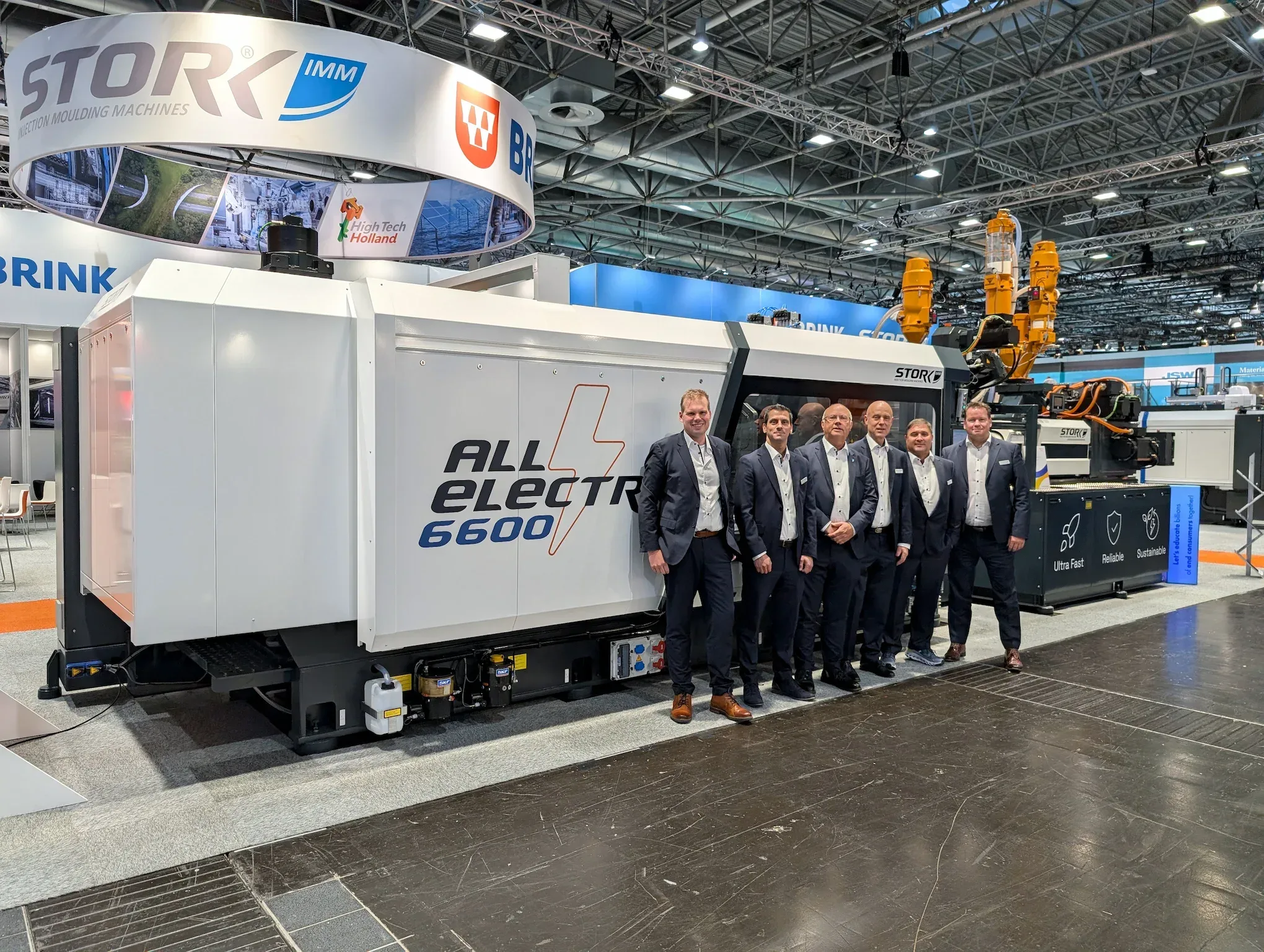 Team Sales Stork IMM at K2025 in front of the All Electric 6600 injection moulding machine.